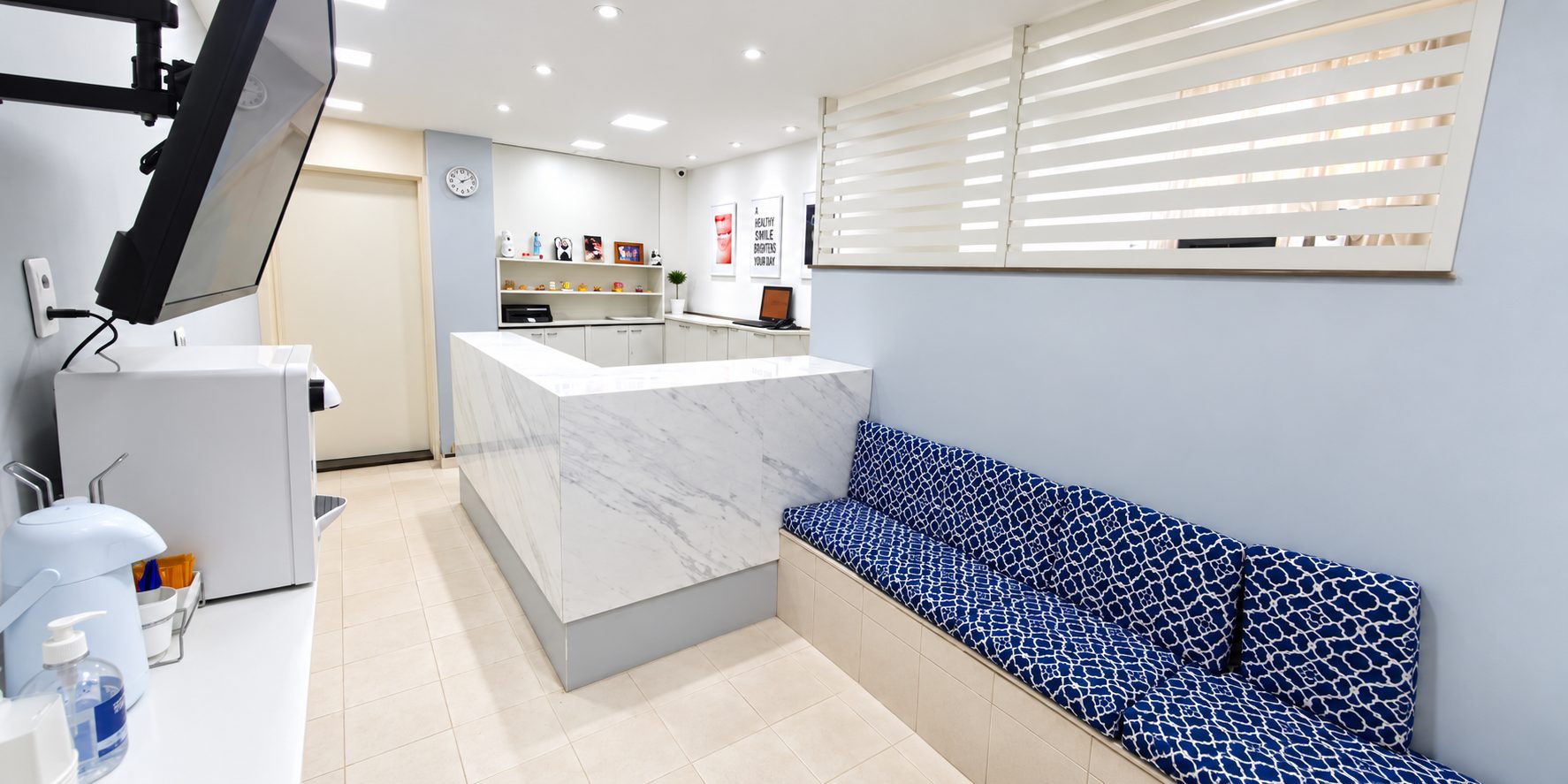 Recepção da Clínica Dr. Enio Lima, com balcão de mármore e sofá azul